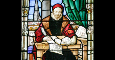 Stained glass depiction of William Tyndale writing at a desk